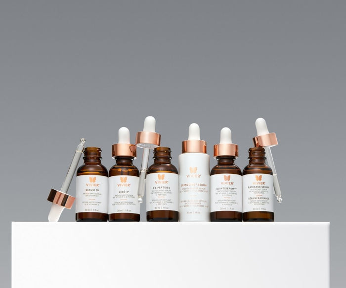 Collection of Vivier pharmaceutical-grade skincare serums in amber glass bottles with rose gold droppers displayed against a light grey background.