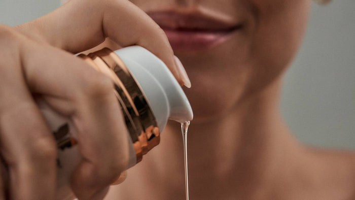 Person pumping a clear gel facial cleanser from a skincare bottle before cleansing.