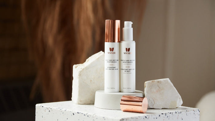 Vivier Daily and Nightly Age-Defying Moisturizers displayed together on a minimalist stone pedestal.