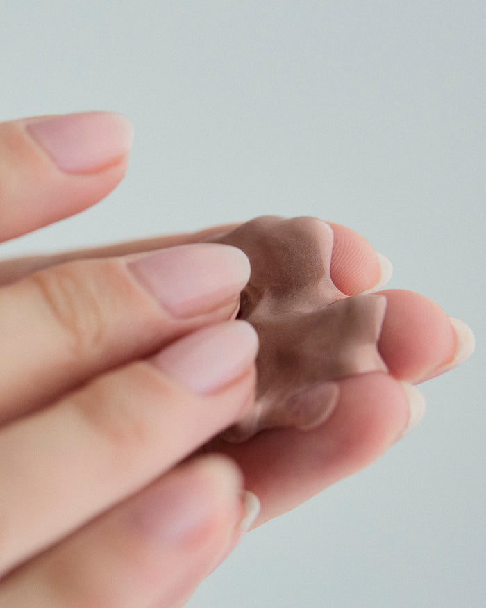 Close-up of fingers holding a dollop of creamy SPF mineral sunscreen..