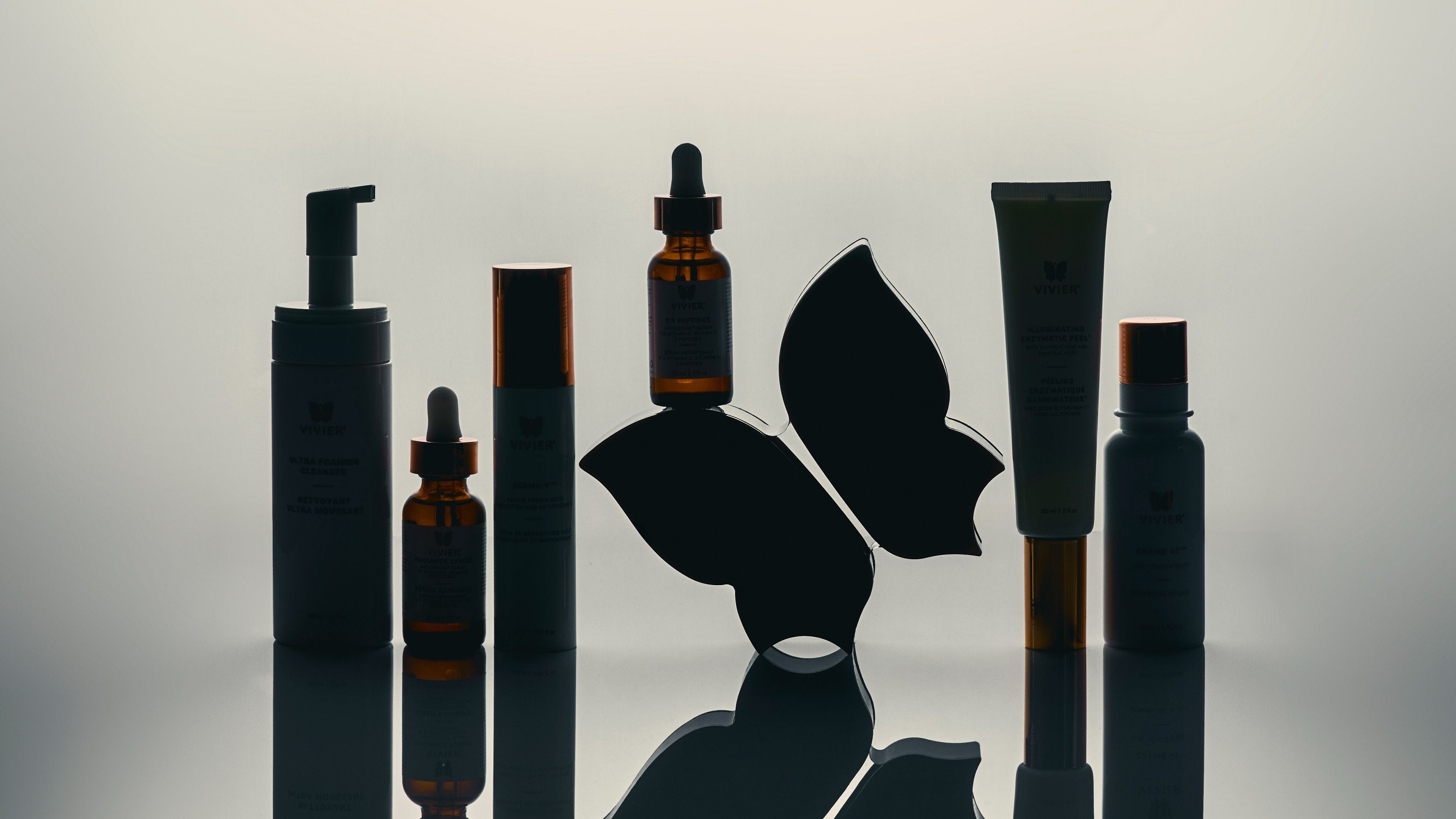 Vivier skincare products arranged with butterfly logo on reflective surface