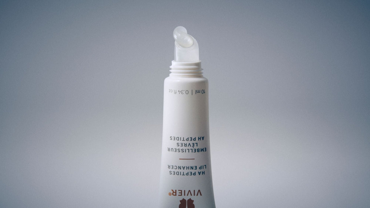Macro view of a Vivier HA Peptides Lip Enhancer applicator with a drop of clear lip treatment.