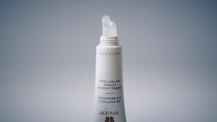 Macro view of a Vivier HA Peptides Lip Enhancer applicator with a drop of clear lip treatment.