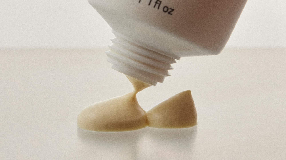 Macro view of a creamy skincare product being squeezed from a tube onto a smooth surface.