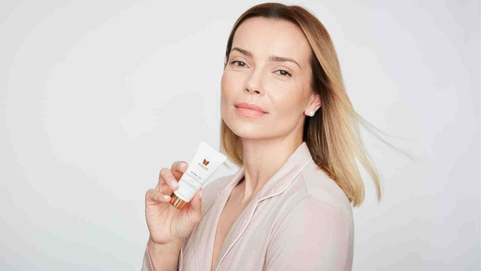 Person holding a tube of Vivier Retinol 1.0% cream in a clean, minimalist skincare portrait.