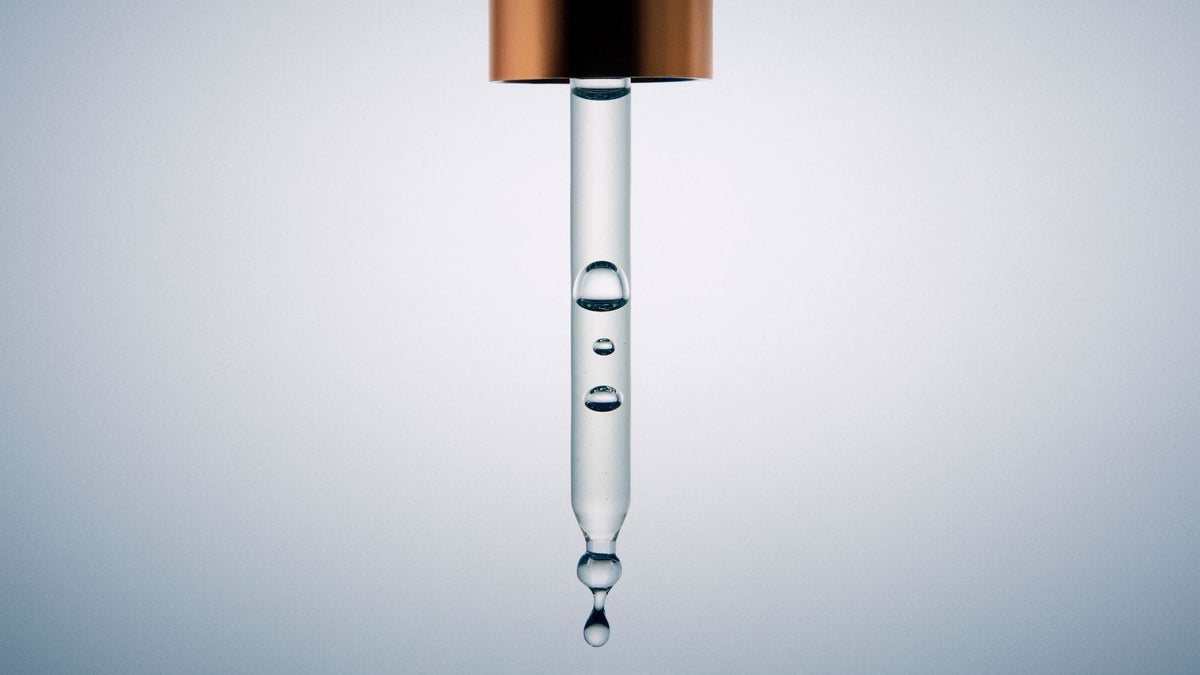 Macro view of a glass dropper filled with clear facial serum, highlighting its lightweight liquid texture.